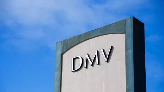 A DMV sign outside against a blue sky.